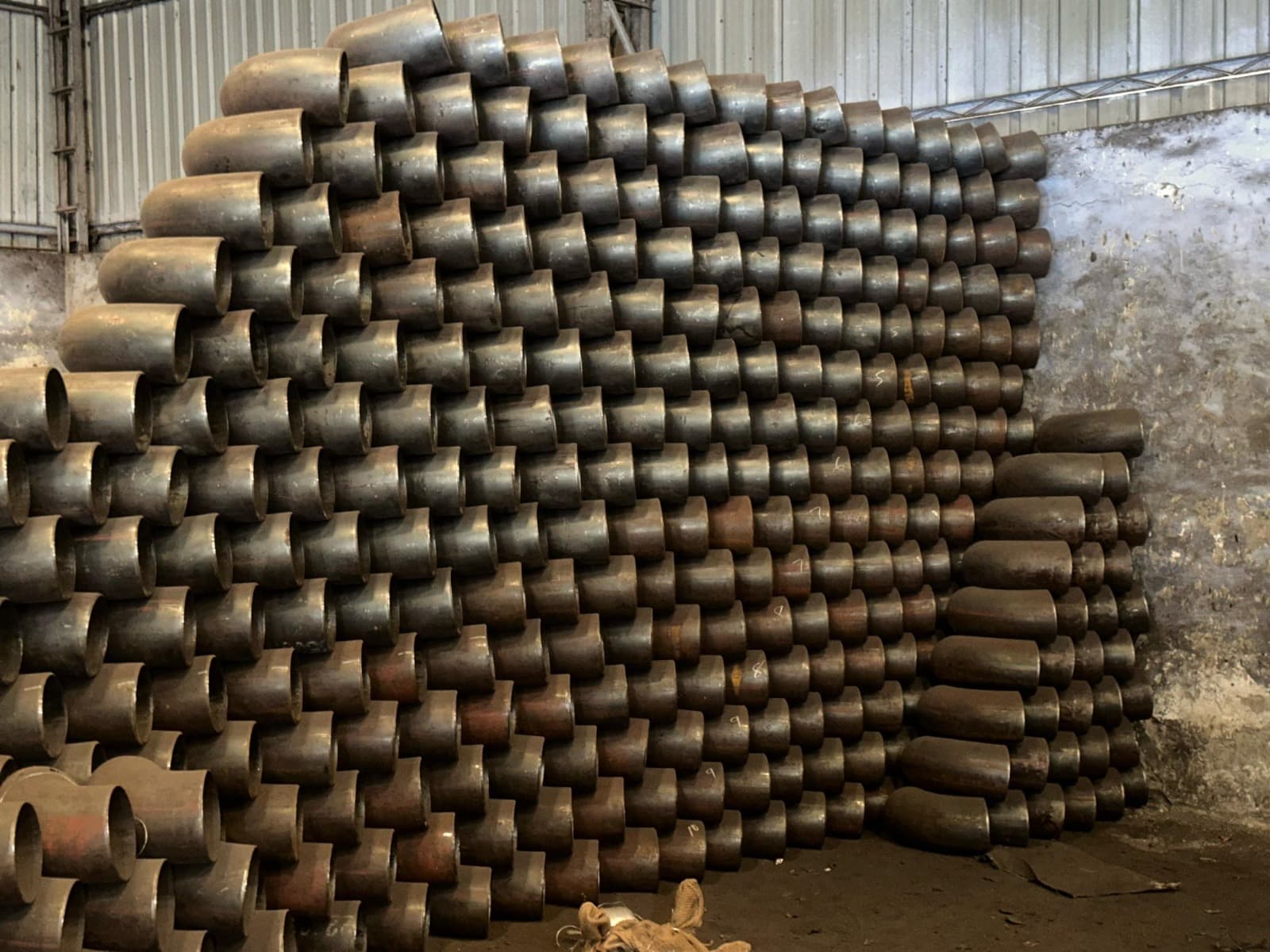 Steel elbows stacked in warehouse